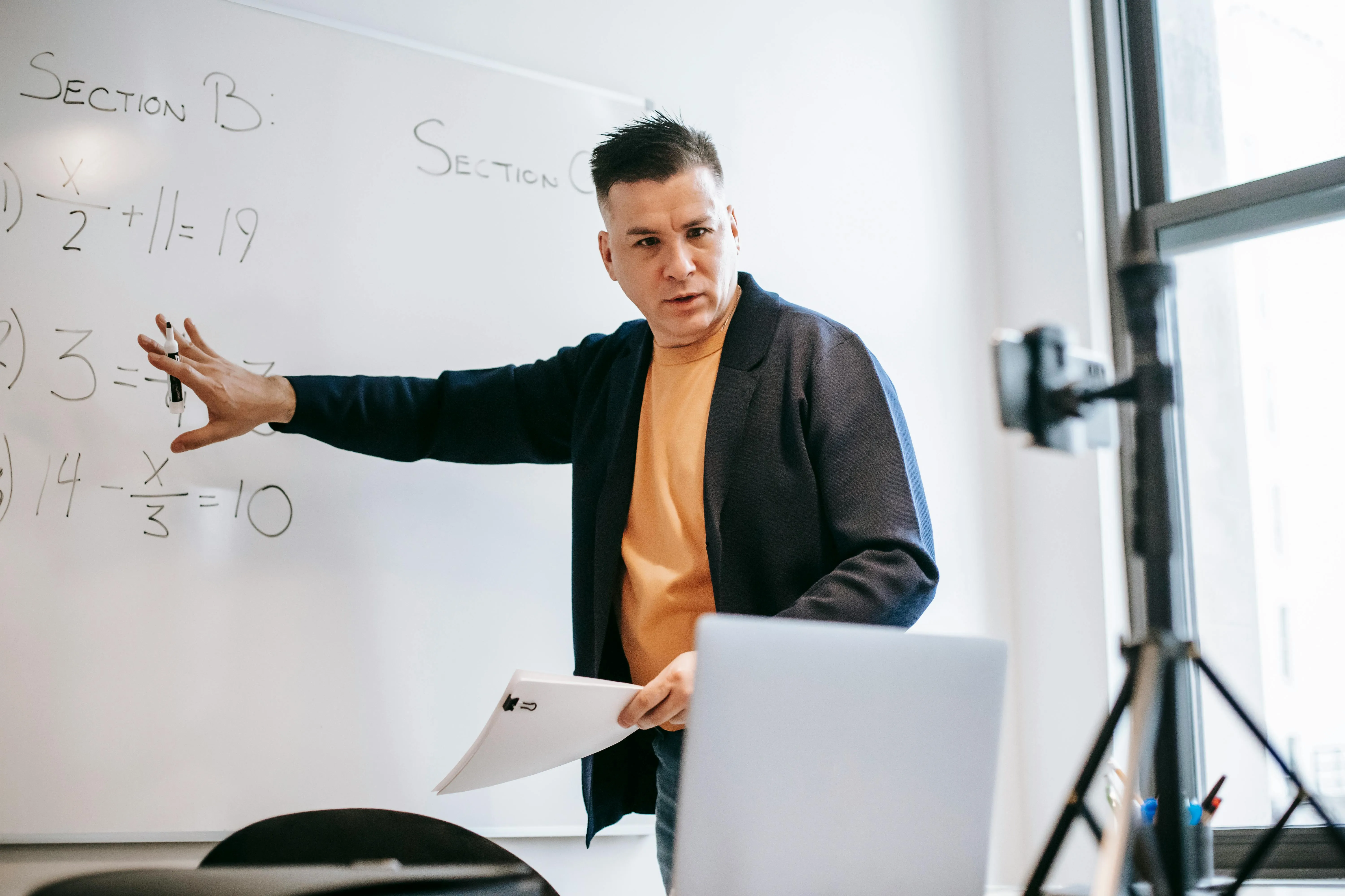 An online educator filming himself giving a lesson on a whiteboard.