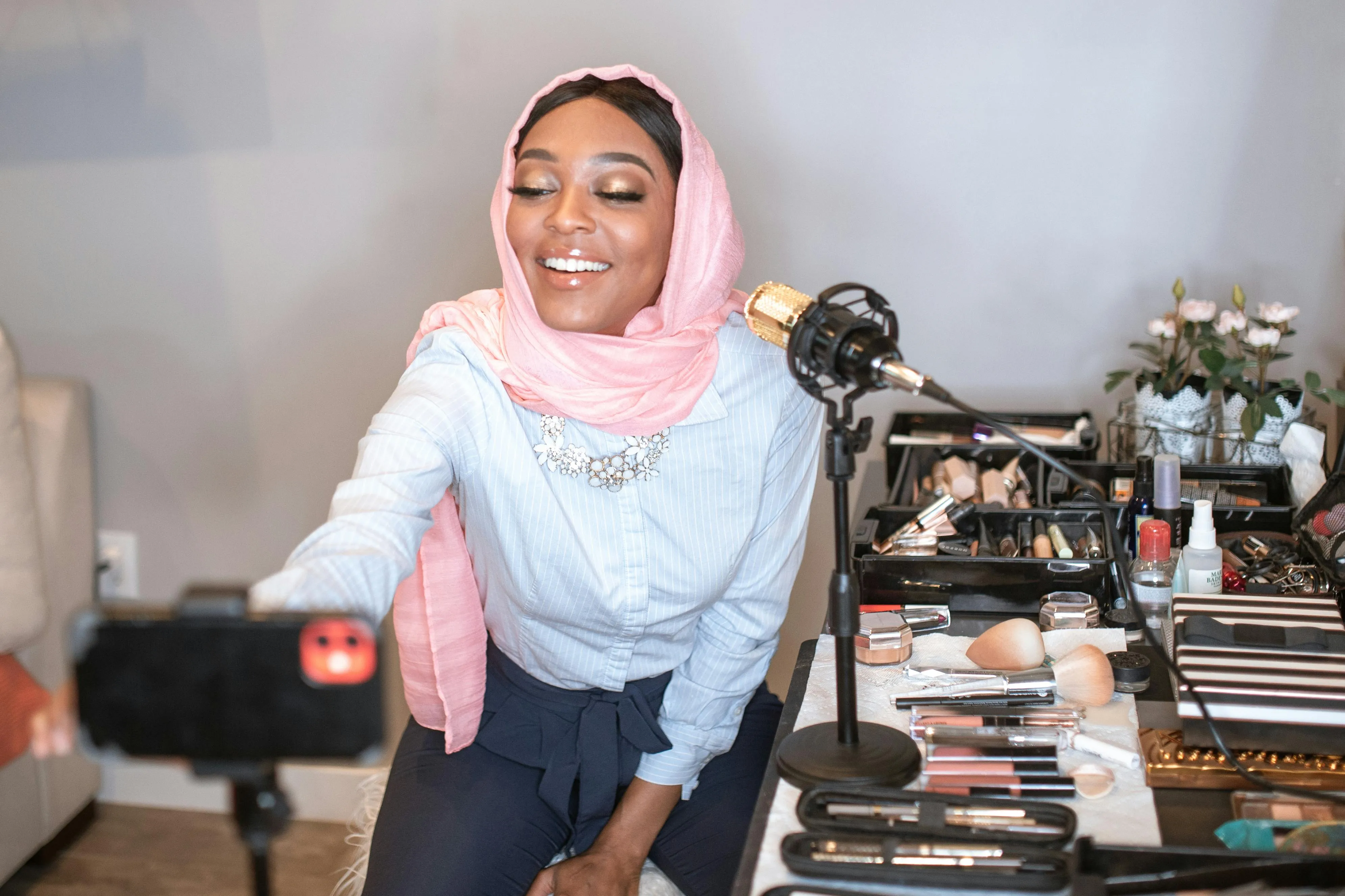 A woman live streaming a makeup tutorial on a smartphone.